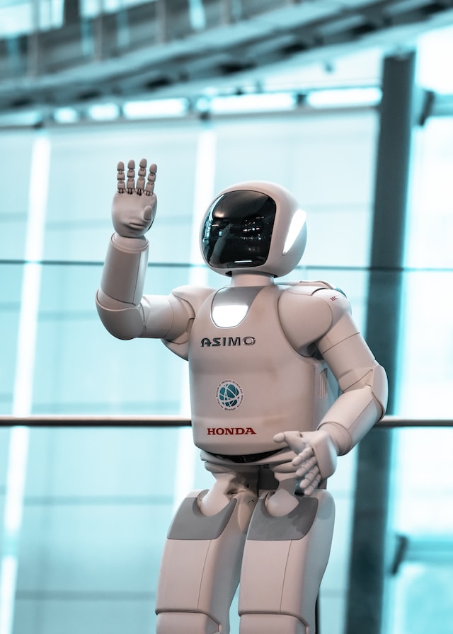 A white robot raising one arm up surrounded by a light blue background.