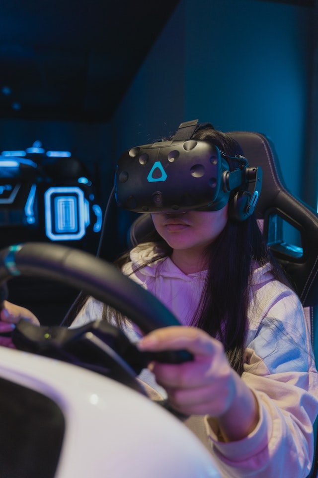 A girl driving a simulator car with VR glasses.